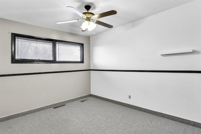 carpeted spare room featuring a ceiling fan, visible vents, and baseboards