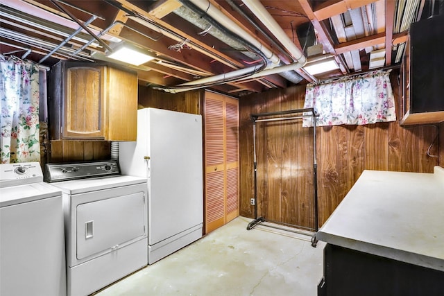 laundry area featuring separate washer and dryer, wood walls, and cabinet space