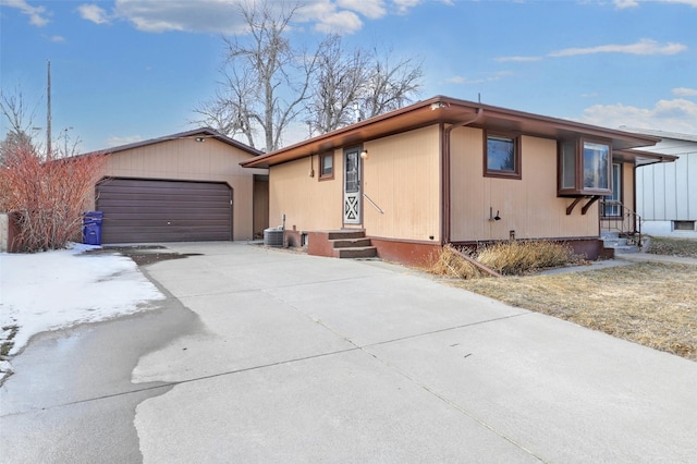 view of front of house featuring an outbuilding, entry steps, central AC unit, a garage, and driveway