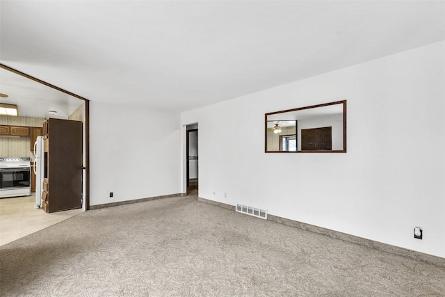 empty room featuring light colored carpet, visible vents, and baseboards