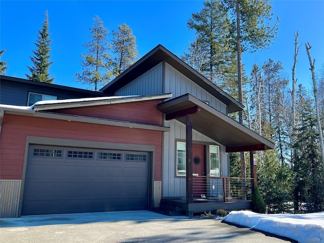 view of front of home with covered porch, driveway, board and batten siding, and a garage