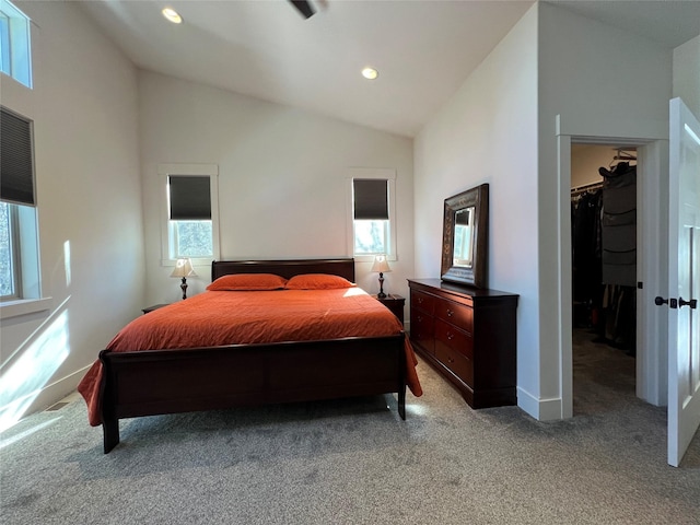 bedroom with light colored carpet, lofted ceiling, multiple windows, and a spacious closet