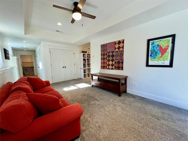 carpeted living area featuring visible vents, baseboards, a raised ceiling, ceiling fan, and recessed lighting