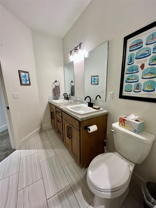 bathroom featuring double vanity, a sink, toilet, and baseboards