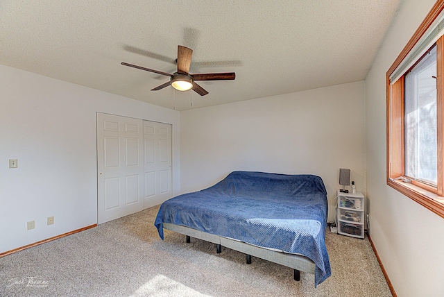 bedroom featuring baseboards, ceiling fan, a textured ceiling, carpet floors, and a closet