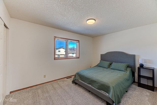 carpeted bedroom with a closet, a textured ceiling, and baseboards