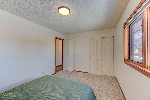 unfurnished bedroom with a textured ceiling, a closet, baseboards, and carpet flooring