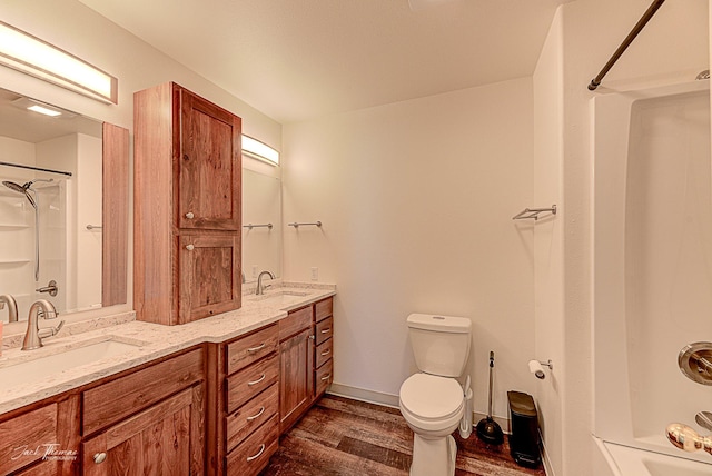 bathroom with toilet, double vanity, a sink, and wood finished floors