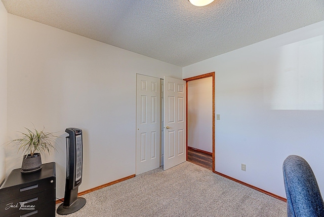 office space with a textured ceiling, carpet floors, and baseboards