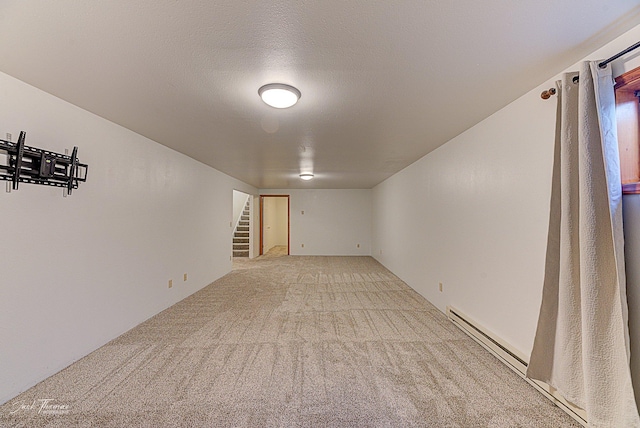 unfurnished room featuring a baseboard heating unit, light carpet, stairway, and a textured ceiling