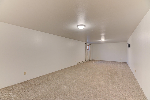 unfurnished room featuring a baseboard heating unit, a textured ceiling, and light colored carpet