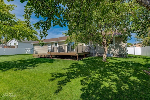 back of house featuring a deck, a lawn, and a fenced backyard