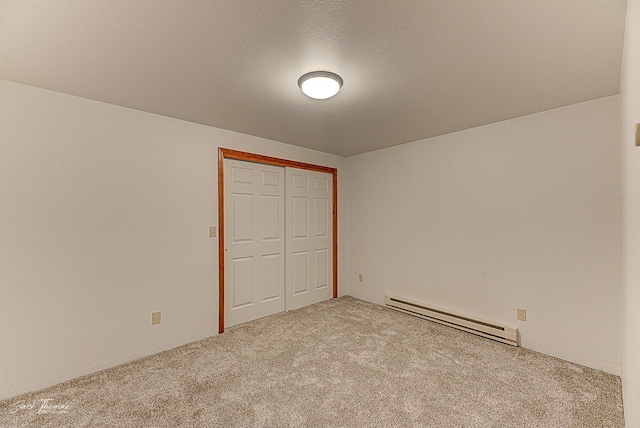 unfurnished bedroom featuring carpet, a closet, a textured ceiling, and baseboard heating