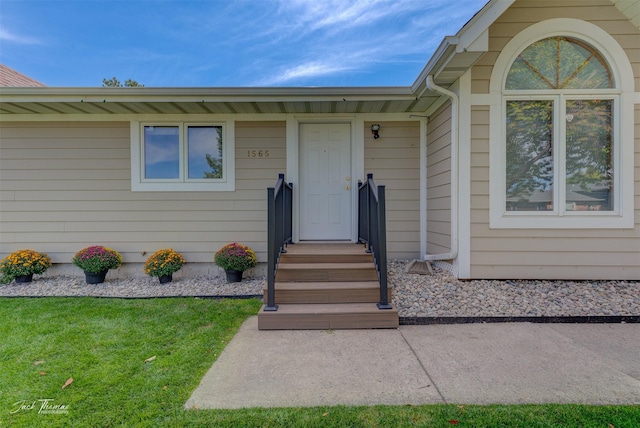 view of exterior entry featuring a lawn