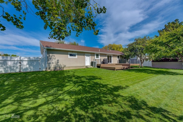 rear view of house featuring central AC unit, fence, a deck, and a lawn