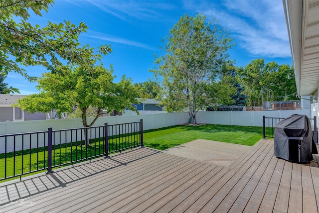 wooden deck featuring a lawn, grilling area, and a fenced backyard