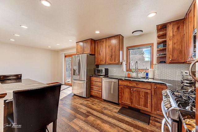 kitchen with stainless steel appliances, dark wood-style flooring, a sink, open shelves, and brown cabinetry