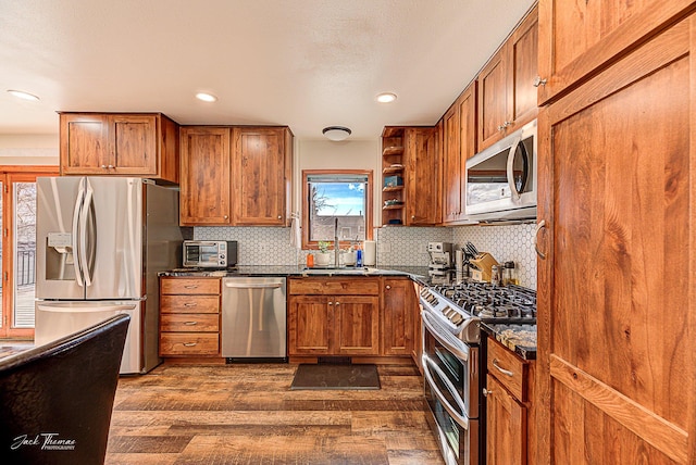 kitchen featuring open shelves, appliances with stainless steel finishes, a sink, and brown cabinets