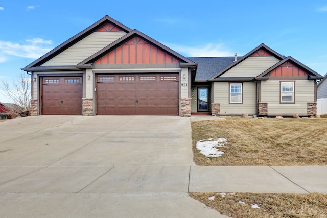 craftsman-style house featuring concrete driveway, stone siding, an attached garage, board and batten siding, and a front yard