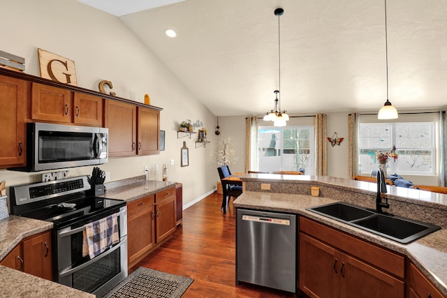 kitchen with stainless steel appliances, dark wood-type flooring, a sink, vaulted ceiling, and brown cabinetry