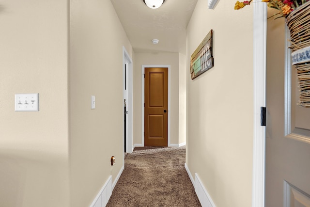 hall with carpet flooring, visible vents, and baseboards