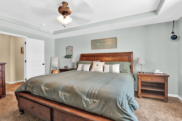 carpeted bedroom with ceiling fan, baseboards, and a tray ceiling