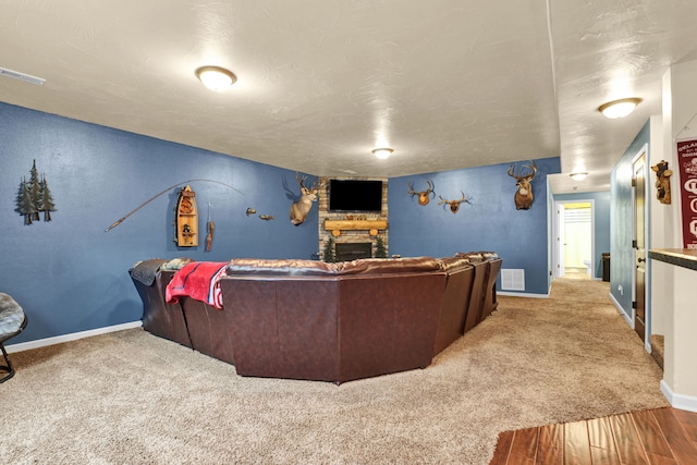 home theater featuring baseboards, visible vents, a fireplace, and carpet flooring