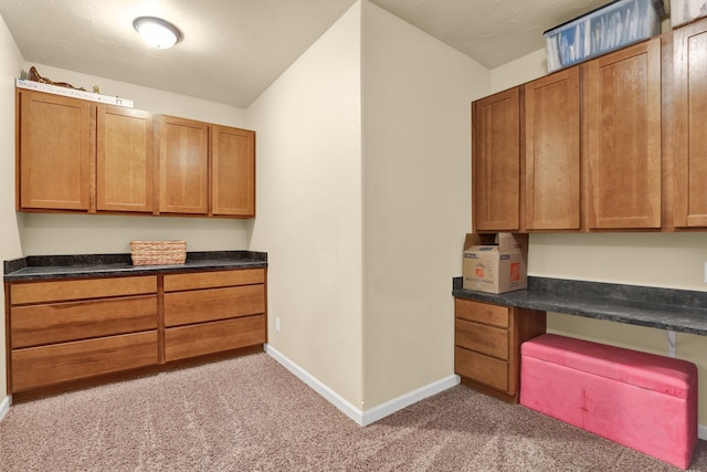 kitchen featuring dark countertops, baseboards, and brown cabinetry