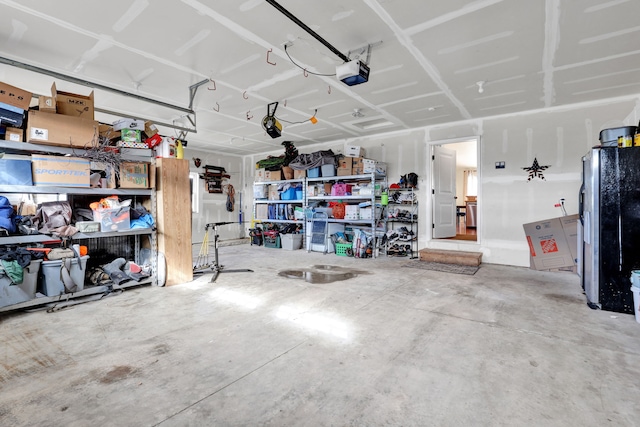 garage with a garage door opener and stainless steel fridge with ice dispenser