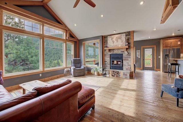 living area featuring ceiling fan, a stone fireplace, recessed lighting, wood finished floors, and baseboards