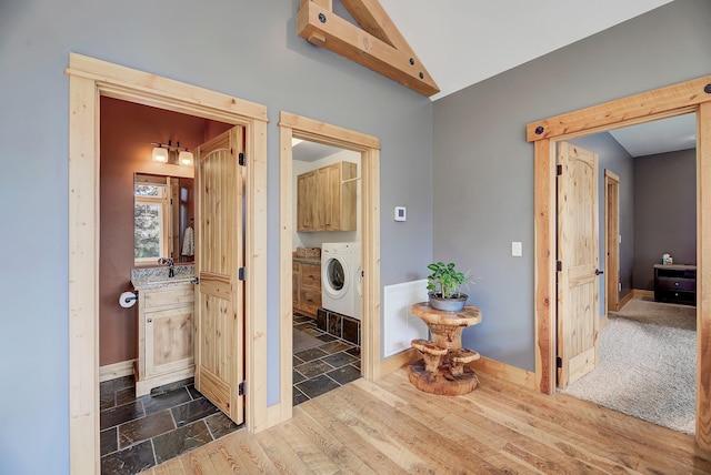 hall featuring washer / clothes dryer, visible vents, dark wood-type flooring, vaulted ceiling, and baseboards