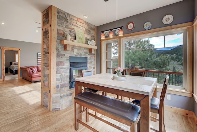 dining space with a stone fireplace and light wood-style flooring