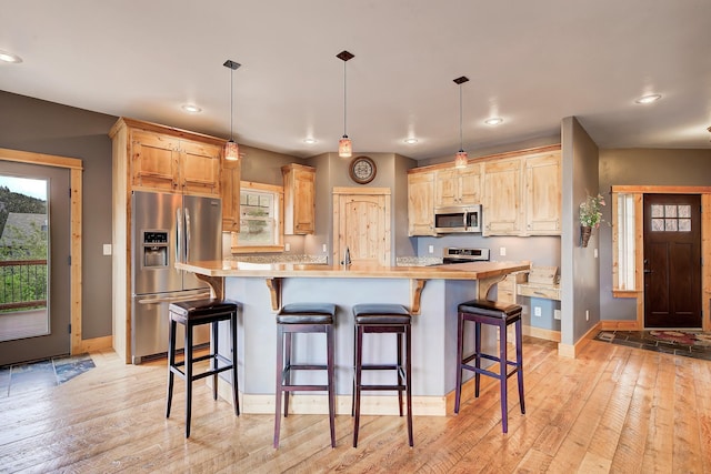 kitchen with light wood finished floors, light brown cabinets, appliances with stainless steel finishes, and light countertops