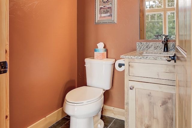 half bathroom featuring toilet, tile patterned flooring, baseboards, and vanity