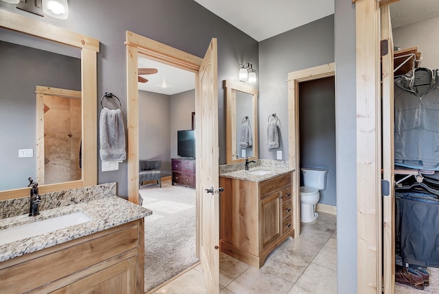 ensuite bathroom featuring ensuite bath, two vanities, a sink, and toilet