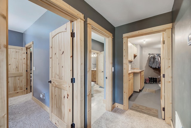 hall featuring light carpet and baseboards