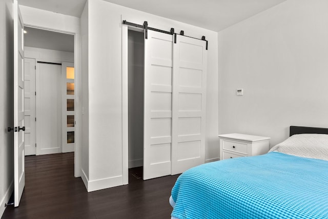 bedroom featuring dark wood-style floors, a barn door, and baseboards