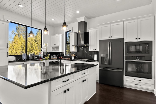 kitchen featuring black microwave, oven, wall chimney exhaust hood, stainless steel fridge, and dark wood finished floors