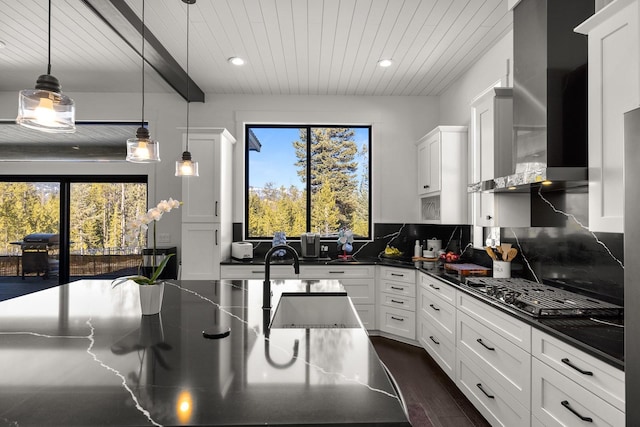 kitchen featuring dark countertops, wooden ceiling, wall chimney range hood, white cabinetry, and backsplash