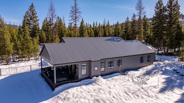 exterior space with metal roof, a forest view, and fence