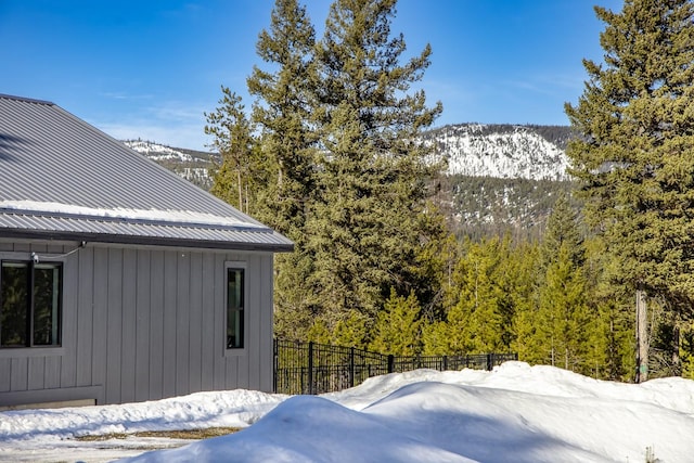 snow covered property with metal roof, fence, and a mountain view