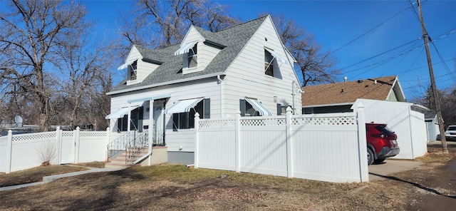 view of side of property with a shingled roof and fence