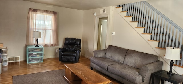 living room with visible vents, stairway, baseboards, and wood finished floors