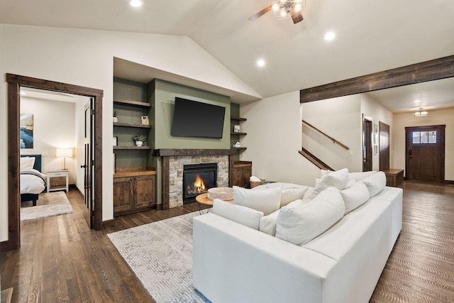 living area with dark wood-type flooring, a fireplace, vaulted ceiling, and a ceiling fan