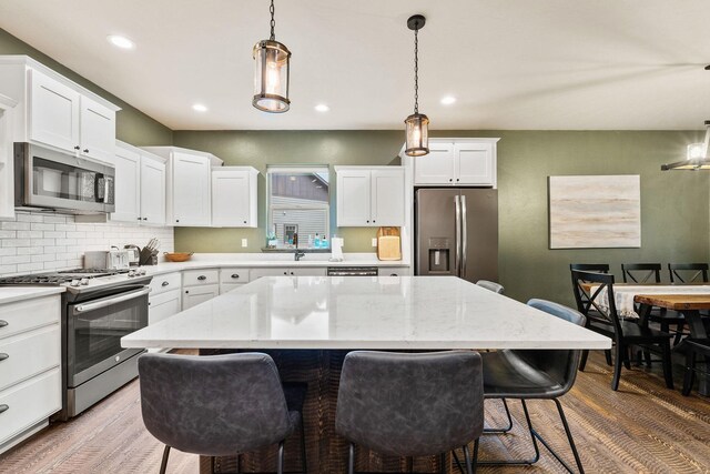 230 Forest Edge Trl, Kalispell, MT 59901 - kitchen with light stone countertops, white cabinets, tasteful backsplash, a sink, and appliances with stainless steel finishes