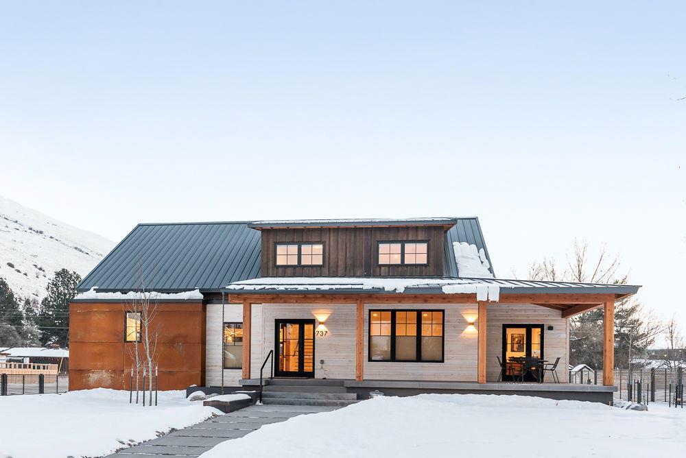 snow covered rear of property featuring a standing seam roof, a porch, and metal roof