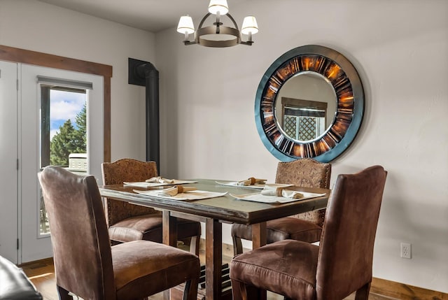 dining room featuring a wood stove, an inviting chandelier, and wood finished floors