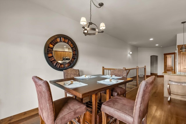 dining area featuring arched walkways, a notable chandelier, recessed lighting, wood finished floors, and baseboards