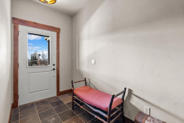 doorway to outside featuring dark tile patterned flooring and baseboards