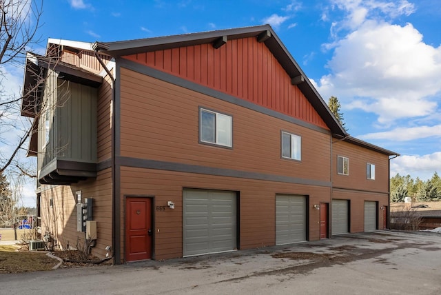 exterior space with an attached garage, central AC unit, and board and batten siding